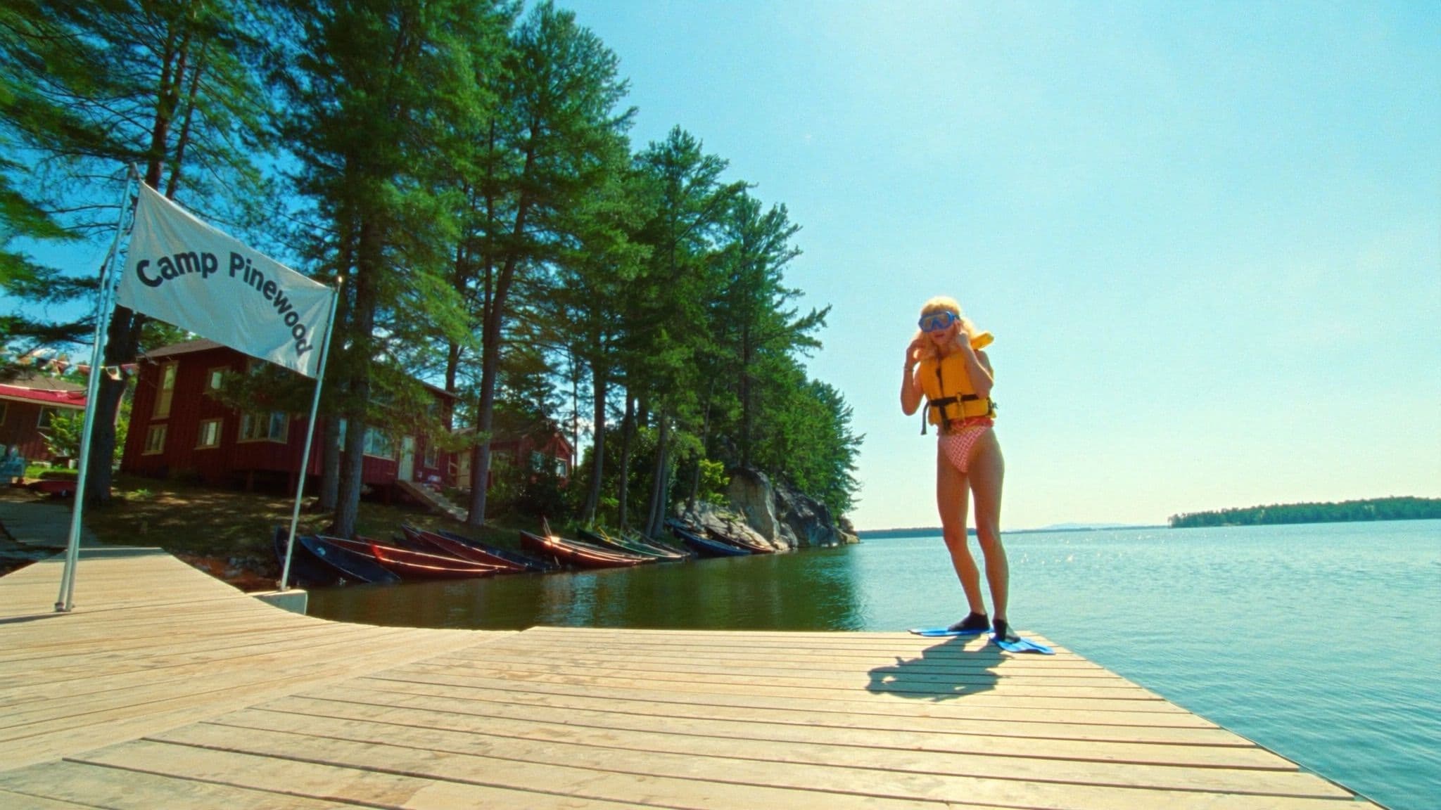 A creator in a life jacket and snorkel mask on a lake dock